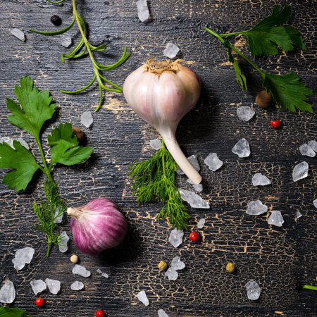 top view of garlic, red, black peppers, sea salt, greenery on cracks black background, close up