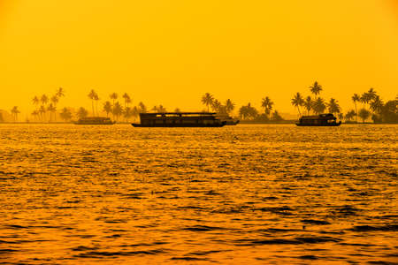 beautiful sunset landscape with houseboats at backwaters Kerala and silhouette of palm trees, travel background, Indiaの写真素材