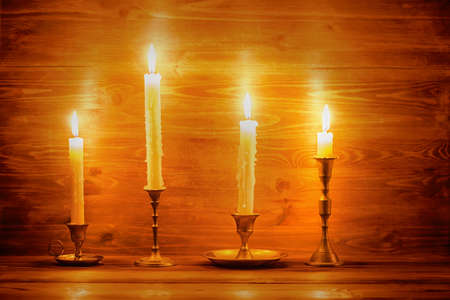 beautiful four candles with different vintage candlesticks on wooden background, close upの写真素材