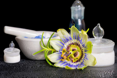 beautiful spa setting of blue passiflora flower, cosmetic salt mortar and fragrance bottle on zen stones with dew, close upの写真素材