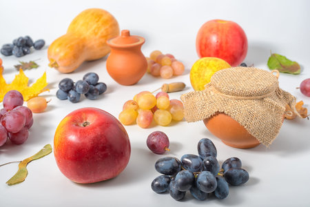 Thanksgiving holiday background with apple, pear, grapes, autumn leaves, rural pot and pumpkins on...