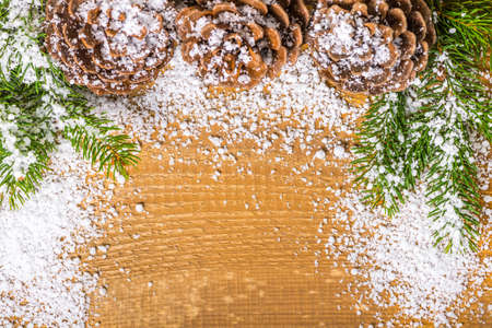 New Year decoration with cones and twigs pine tree on wooden background with snow, close up, top viewの写真素材