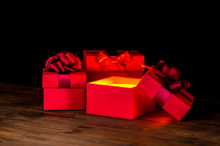greeting opened box with bow and miracle light on wooden background is isolated on black, closeupの写真素材