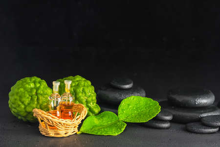 aromatic concept of bergamot, leaf, fragrance oil and zen basalt stones with water drops on black background, close up の写真素材