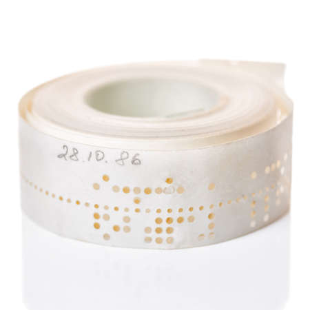white perforated punched tape with old data is isolated on background, close up white perforated punched tape with old data is isolated on background, close up