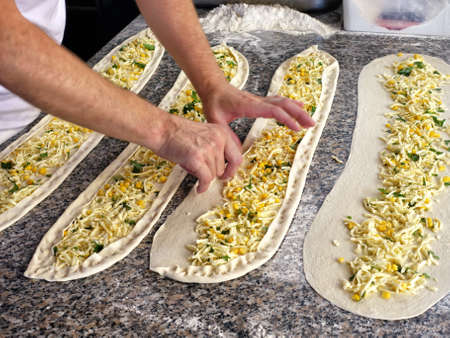 confectioner making turkish cake with cheese, greens, cornの写真素材