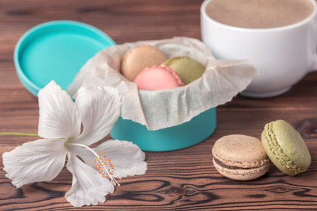 colorful macarons cake in gift box, cup of coffee and white hibiscus flower, holiday conceptの写真素材