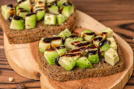 sandwiches with chopped avocado, rye bread toast decorated drizzled with sauce and peppered on...