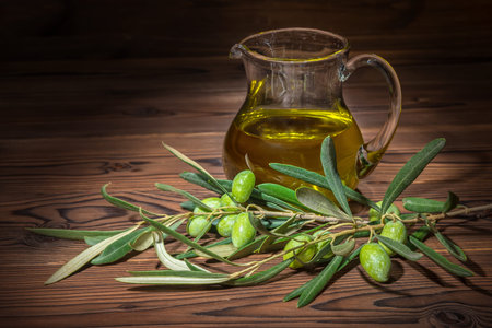 green branches of olive tree with berries and fresh oil on wooden background, rustic styleの写真素材