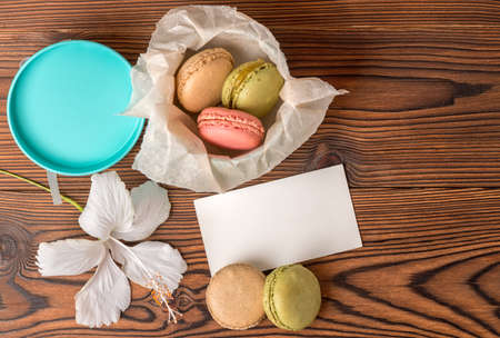 top view of colorful macarons cake in gift box, empty blank,  and hibiscus flower on wooden background, copy spaceの写真素材