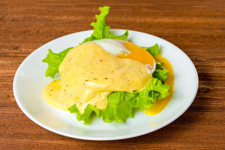 Poached eggs, ham, lettuce leaf and delicious buttery fresh hollandaise sauce on toasted English muffin. Eggs Benedictの写真素材