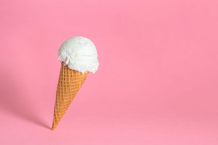 creative concept of close up falling single wafer cone with ice cream on pink background, copy space の写真素材