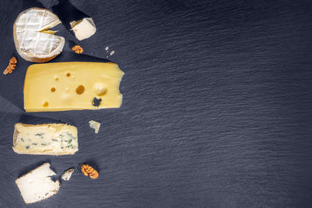 top view of tasty various types of cheese on black slate stone background, Italian, French food, concept of dairy productsの写真素材