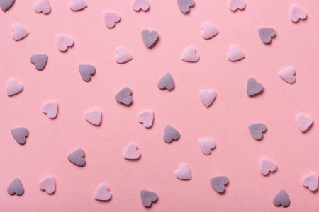 Beautiful sweet pink sprinkles of heart shapes over pink background, concept of St. Valentines Day