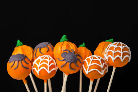 concept of Halloween party with glazed cake pops on black backgroundの写真素材