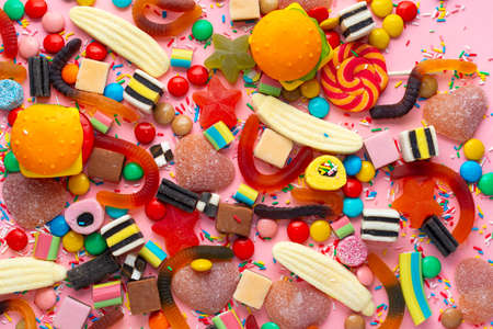 candies with jelly and sprinkles colorful array of different childs sweets and treats over pink like festive backgroundの写真素材