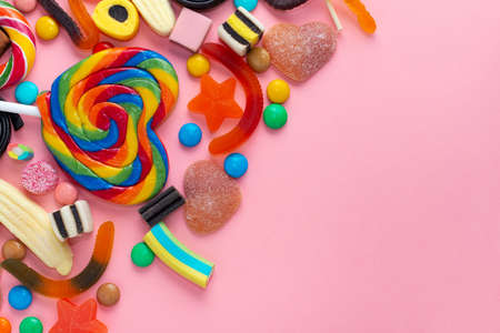 mixed colorful sweets lollipops and candies over pink like festive background with copy spaceの写真素材