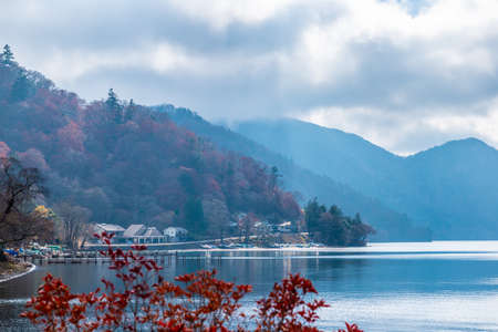 beautiful autumn view of lake Chuzenji with houses, trees and mountains near Nikko, Japan, travel backgroundの写真素材