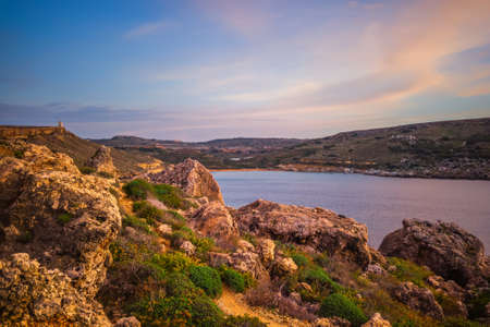 beautiful sunset and seascape view with mountains of Golden Bay, Malta, travel backgroundの写真素材