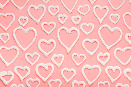 sweet meringue kiss cookies of heart shapes over pink background, concept of St. Valentine's Day