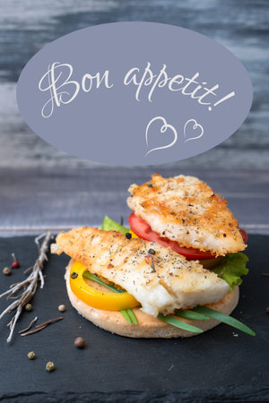 Fish grilled with tomato, pepper, green onion on the bread with sign Bon appetitの写真素材