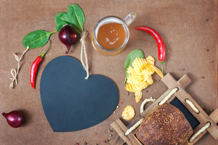 A board for inscriptions in the form of heart, beer and snack on plywood backgroundの写真素材
