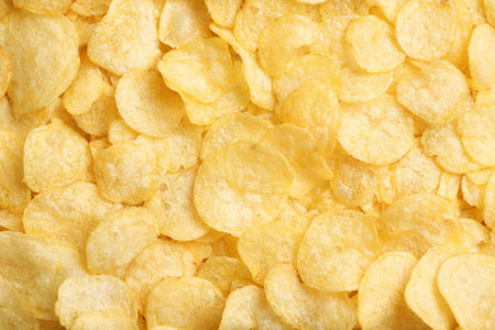 Delicious potato chips as background, top view