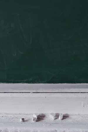 Green blackboard and chalk pieces on shelf in classroom. Mockup for designの写真素材