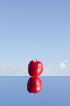 one red apple with refelction on mirror and skyの写真素材