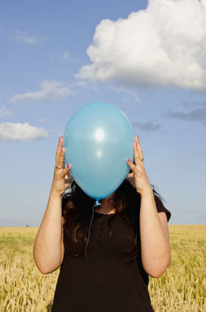 young woman holding azure balloon and sky backgroundの写真素材