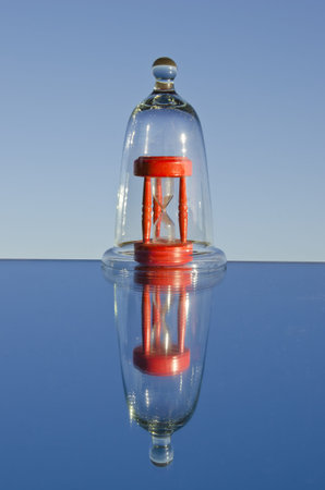 red vintage sandglass in the glass jar and mirror