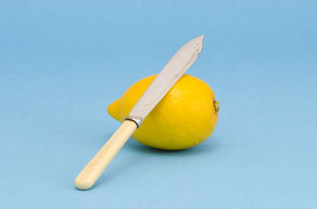 one yellow lemon with knife on azure backgroundの写真素材