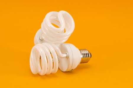 two modern energy saving bulbs on yellow background