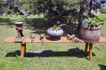wooden bench in farm with flowers and antique meat grinderの写真素材