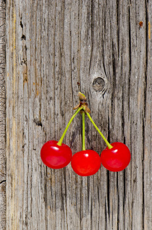 Three sweet cherries on old wooden background