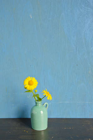yellow spring flowers in small green vaseの写真素材