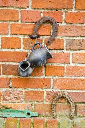 old red bricks wall with rusted horseshoe and black jugの写真素材