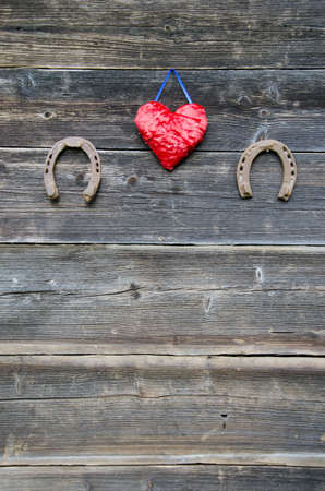 two rusty horseshoe and red heart symbol on old farm wooden wallの写真素材