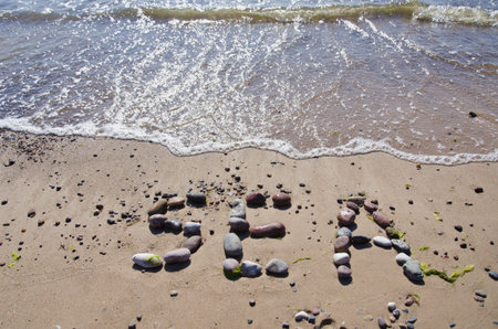 word sea concept on beach sand and waves. Stone wordの写真素材