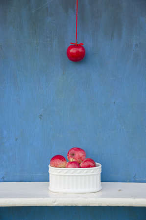 hanging red apple on string and white vase with fruits. Healthy life conceptの写真素材