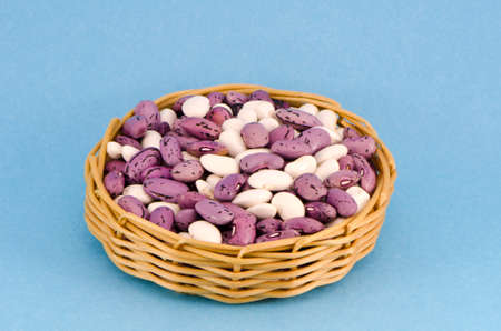 fresh beans in wicker wooden plate on blue backgroundの写真素材