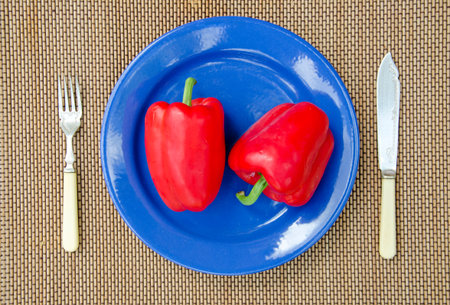 two red peppers in blue plate and vintage flatwareの写真素材