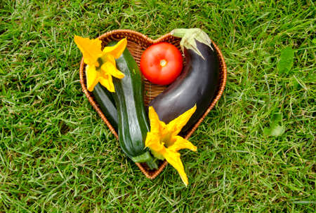 heart form wicker basket with vegetable. Tomato,zucchini,courgette flowers and eggplantの写真素材