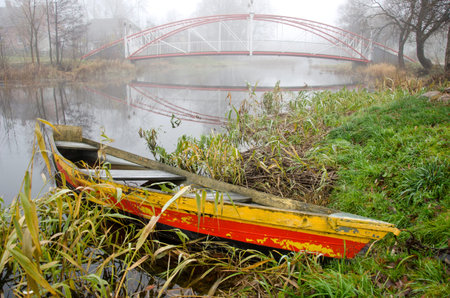 colorful old boat and river with bridge in autumn time morning mistの写真素材