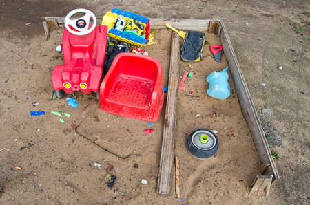 old playground childrens sandbox with toys in autumn after rainの写真素材