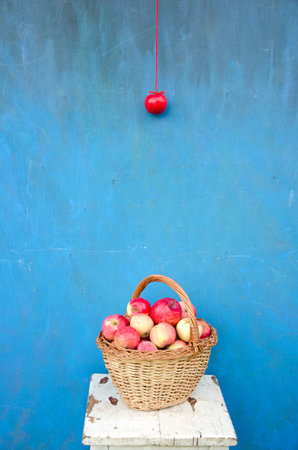 wicker wooden basket with red apples on seat near blue wall. Healthy lifeの写真素材