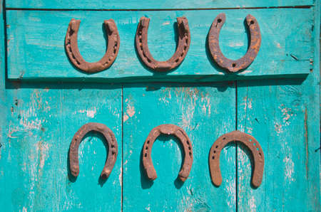 six antique rusty horseshoe on old green wooden farm barn doorの写真素材