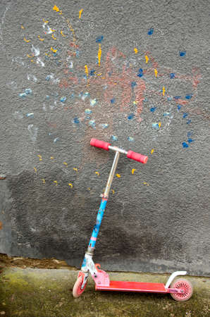 used child  kick scooter near colorful house wallの写真素材