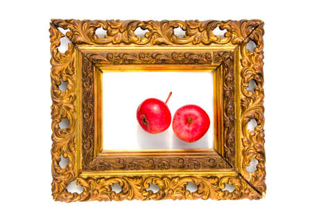 two red beautiful apple in ancient antique golden picture frame isolated on whiteの写真素材