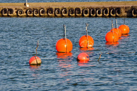 group orange buoy in sea on water near pier